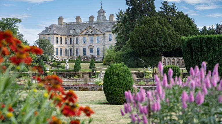 The Italian Garden at Belton Estate with orange and pink flowers in the foreground, and the fountain and house in the background.